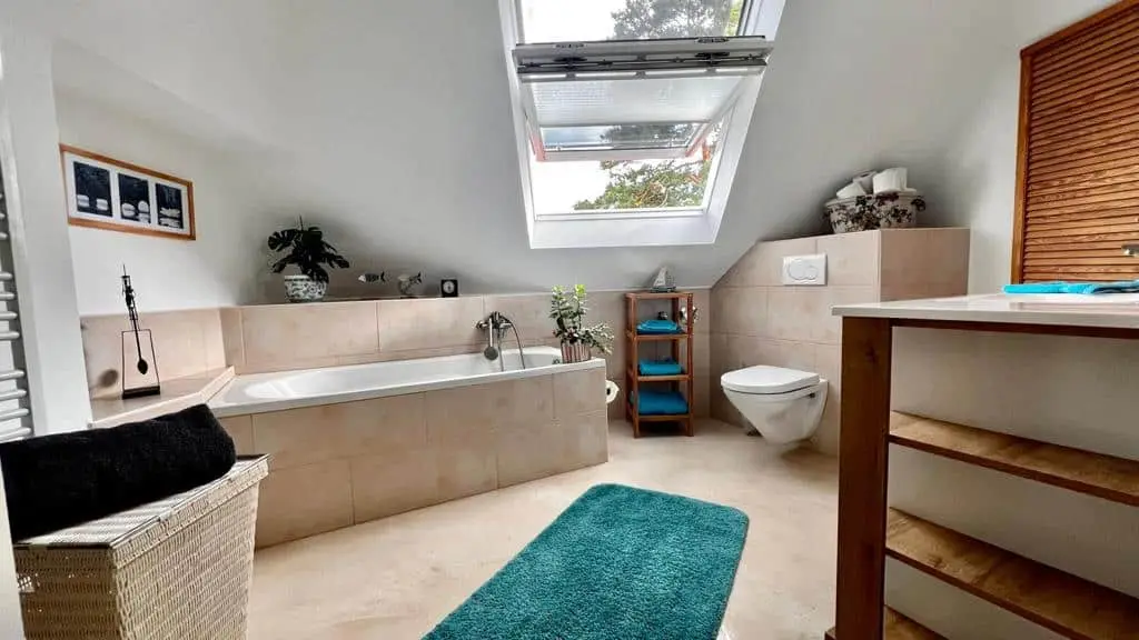 Badezimmer mit Badewanne unter dem Dachfenster und türkisfarbenen Akzenten