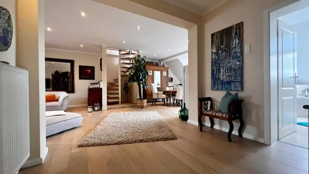 Offener Wohnbereich der Wohnung „Zur Auszeit“ mit Holzdielen, Wendeltreppe und Antikmöbeln