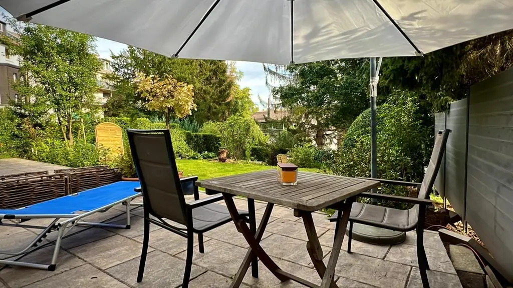 Gartenterrasse der Villa mit Sonnenschirm, Tisch und Liegestuhl