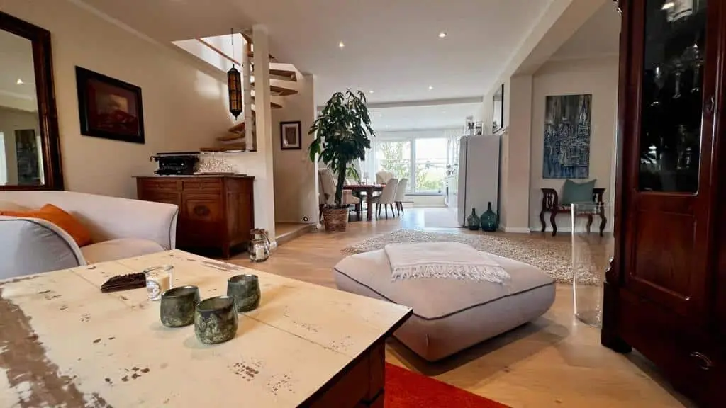 Großzügiger Wohnbereich der Ferienwohnung „Zur Auszeit“ mit Sofa, Holzdielen und Wendeltreppe