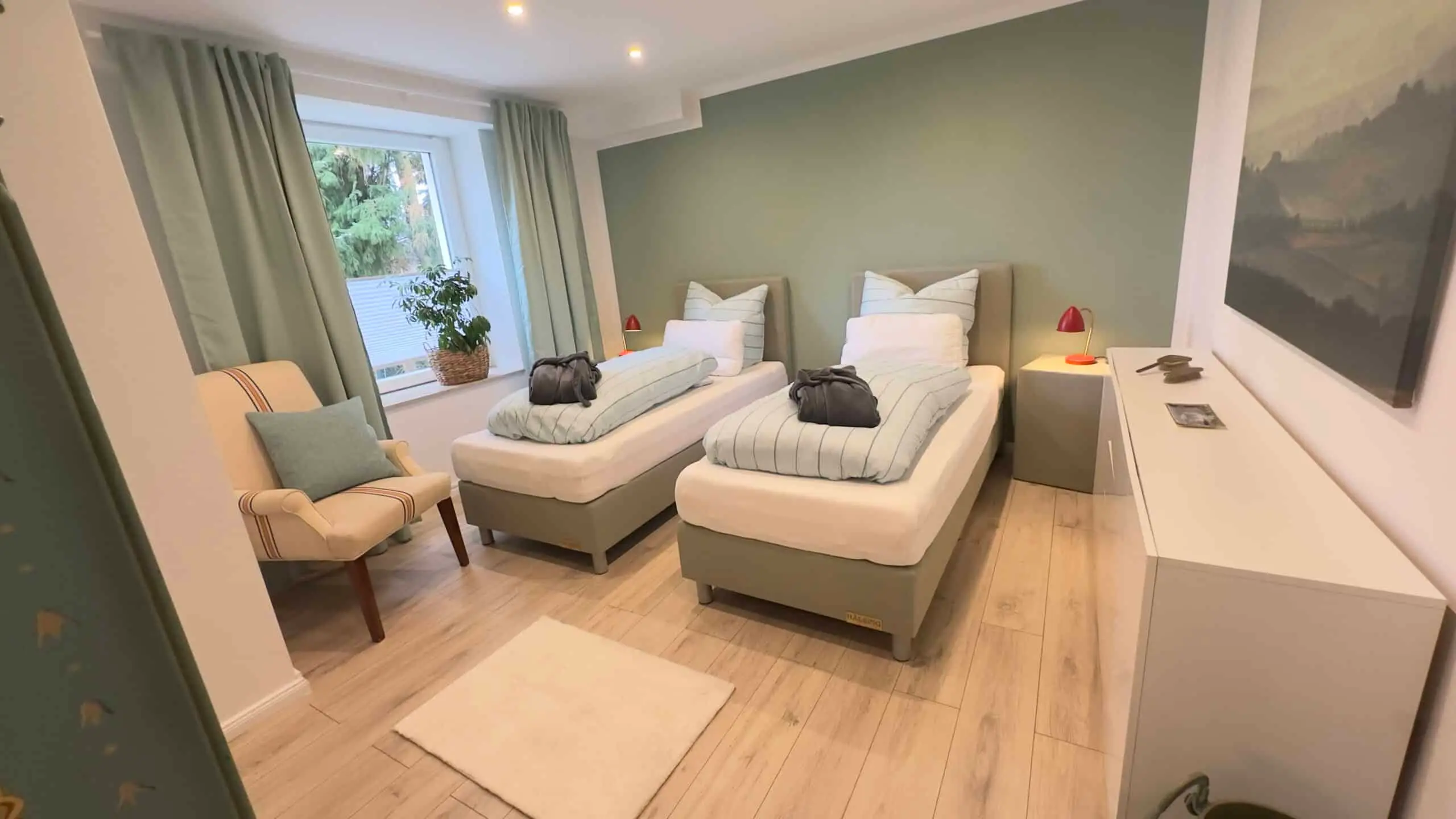 Schlafzimmer mit zwei Einzelbetten und salbeigrüner Wand
