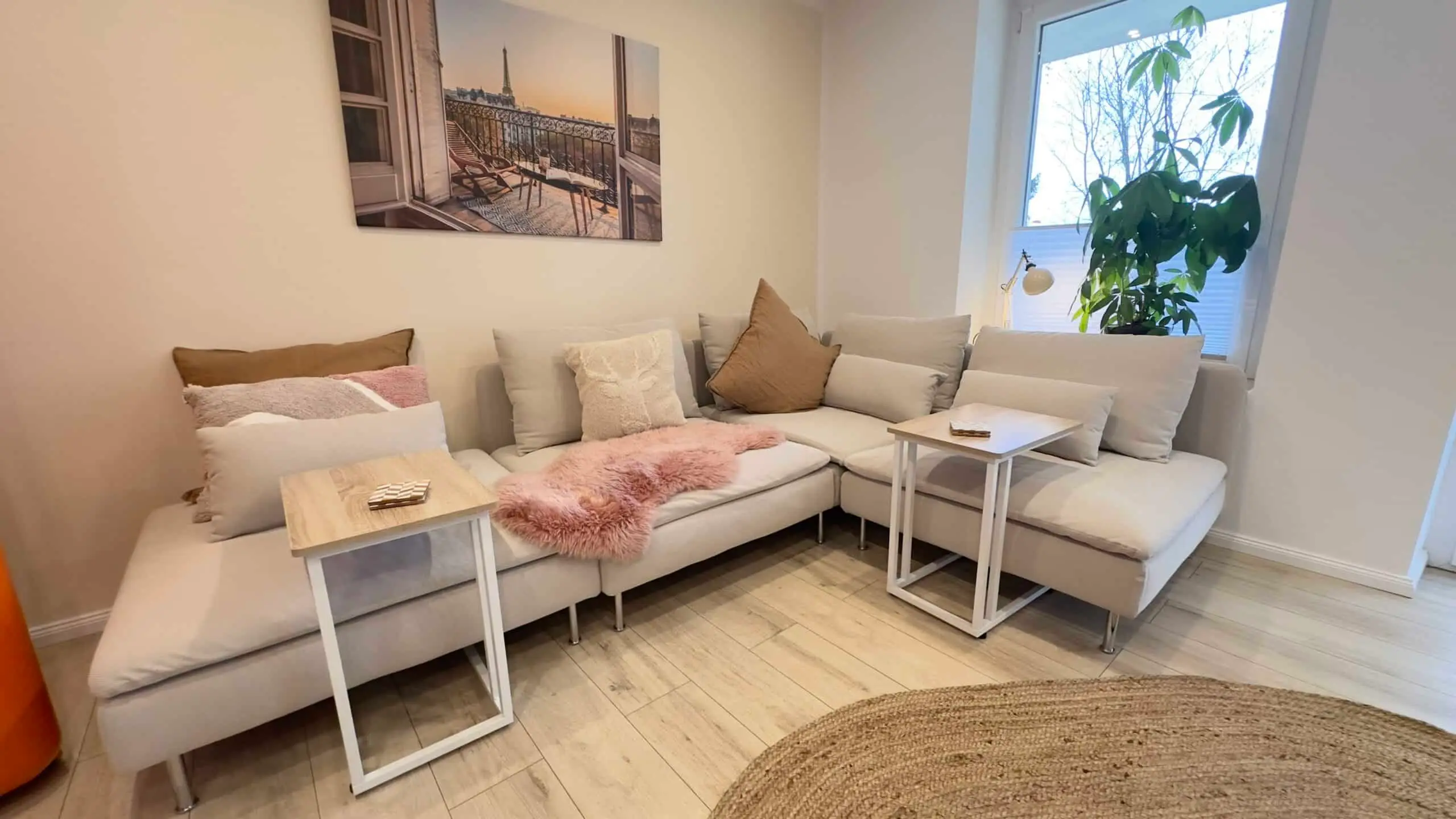 Gemütliche Sofaecke mit Kissen, Fellen und Zimmerpflanze am Fenster