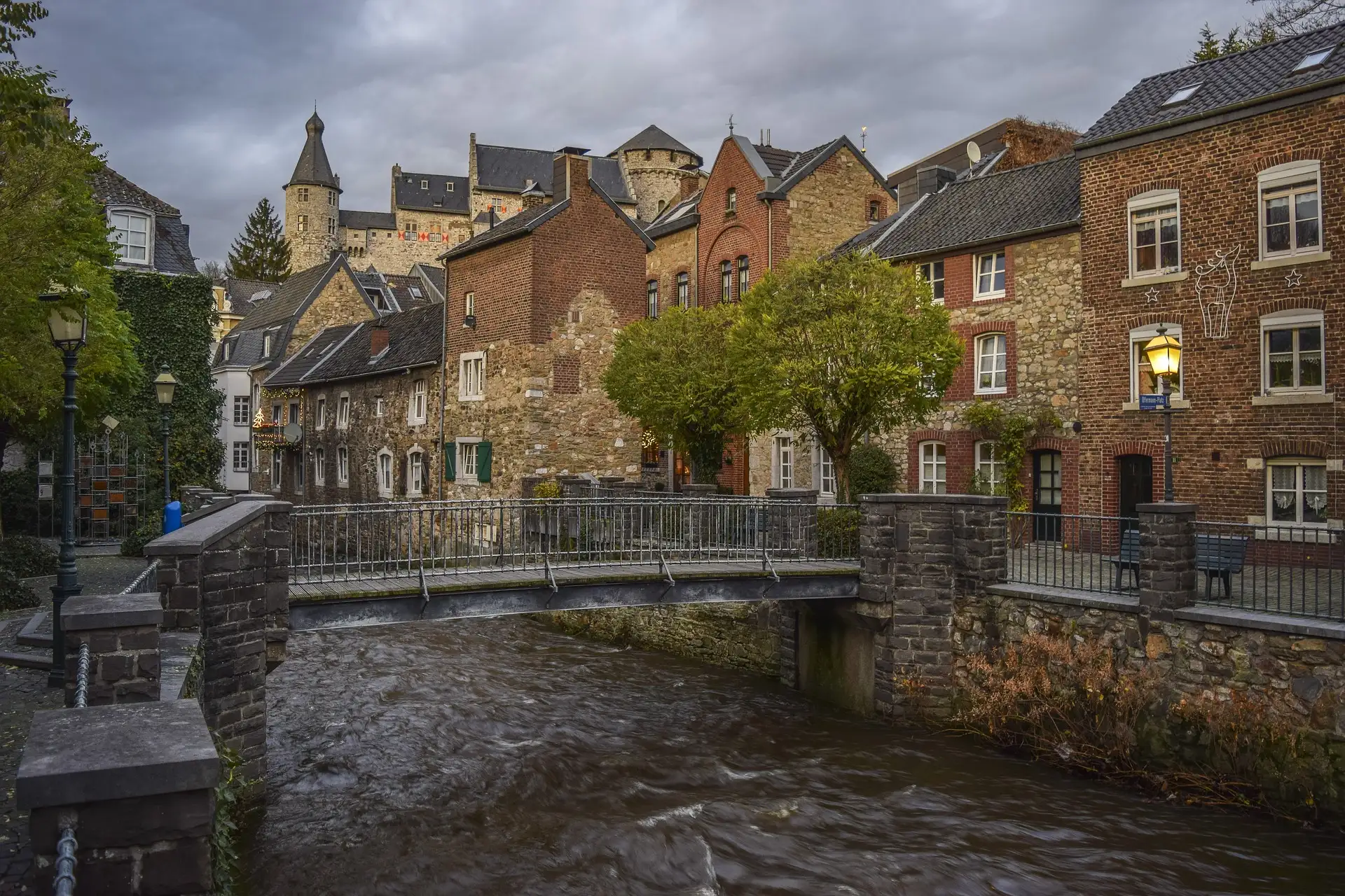 Historische Häuser am Vichtbach in Stolberg, darüber thront die Burg