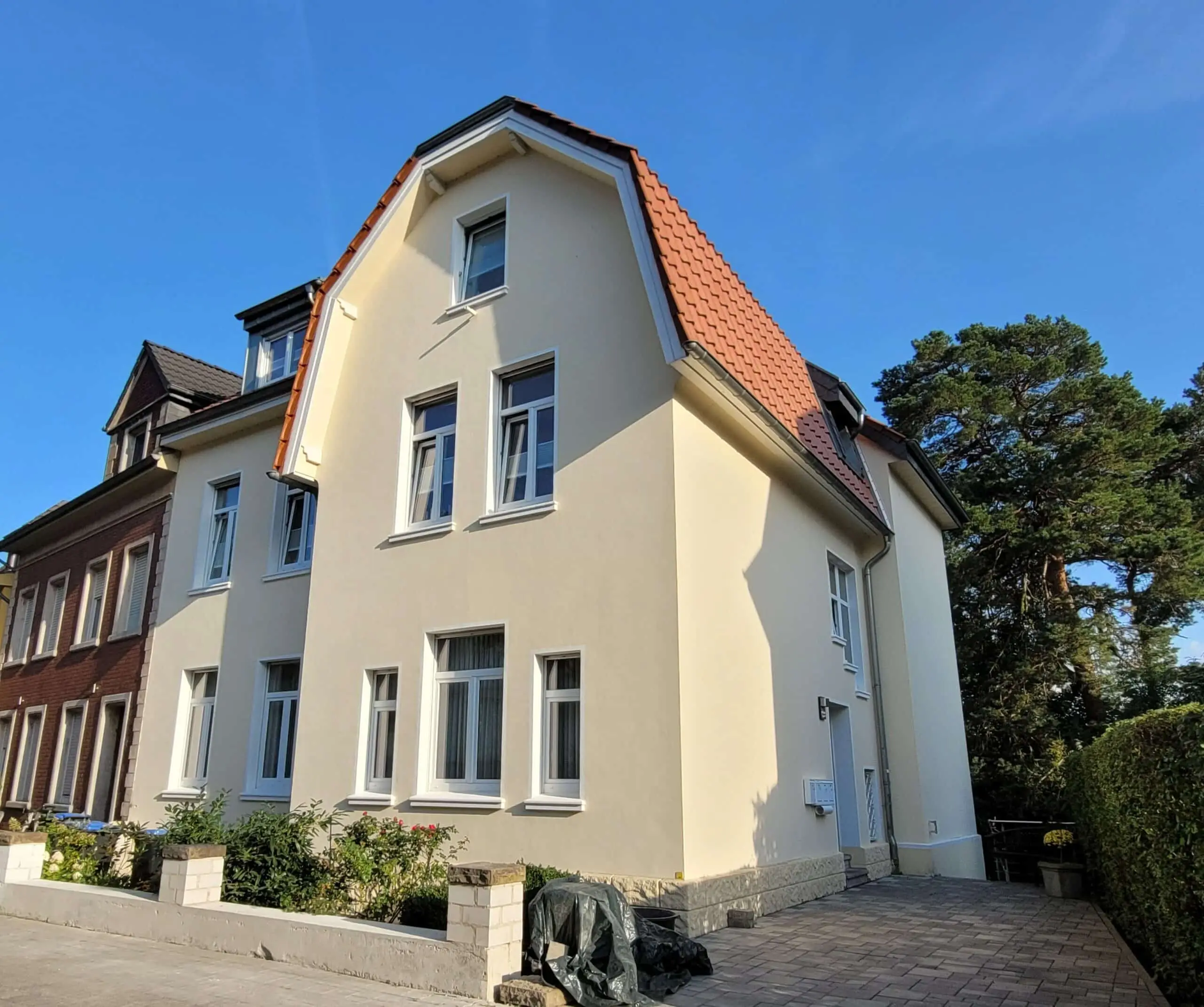 Die Jugendstilvilla Sonnenschein in Stolberg: heller Altbau mit rotem Ziegeldach, davor der private Parkplatz